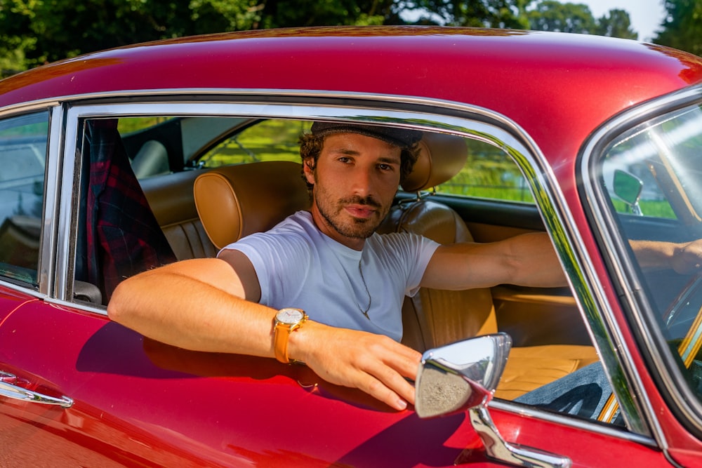 man in white polo shirt sitting on red car seat