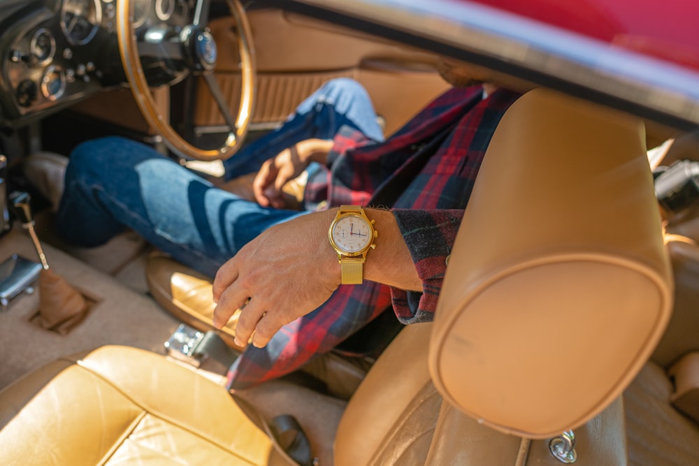 person in blue red and white plaid dress shirt sitting on brown leather car seat