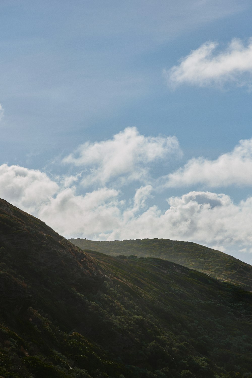 green and brown mountain under white clouds and blue sky during daytime