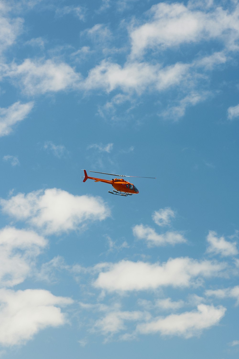 red and white helicopter flying in the sky