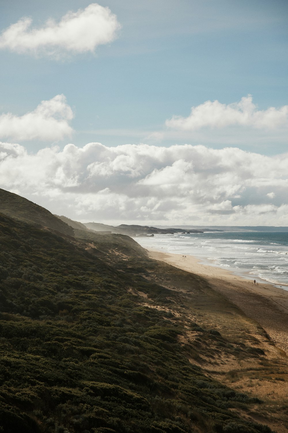 brown sand beach under white clouds and blue sky during daytime