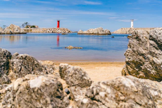 white and red lighthouse on gray rocky shore during daytime
