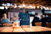 Close-up of trivia cards and buzzing game devices on a wooden bar table during a lively event.