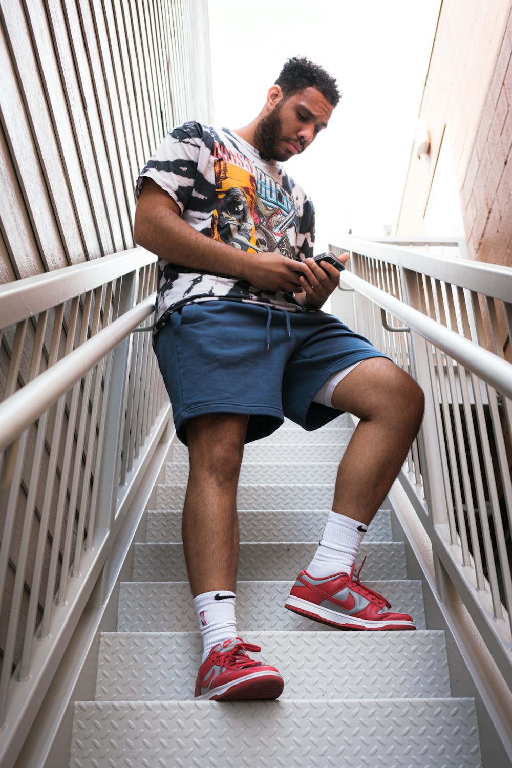 woman in blue white and red floral shirt and black skirt sitting on white wooden staircase