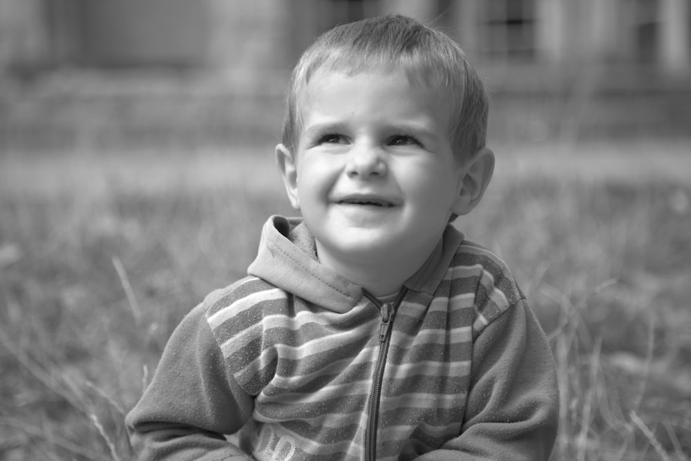 Foto en escala de grises de un niño con una sudadera con capucha con cremallera