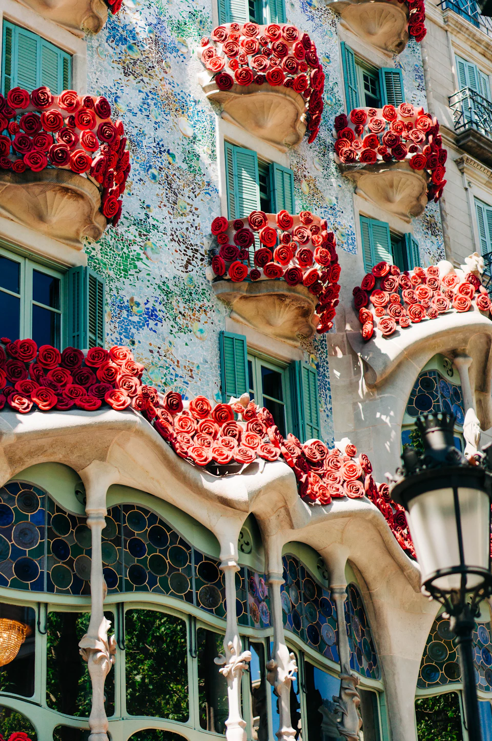 Casa Batlló's balconies and mosaic facade decorated with red roses for Sant Jordi