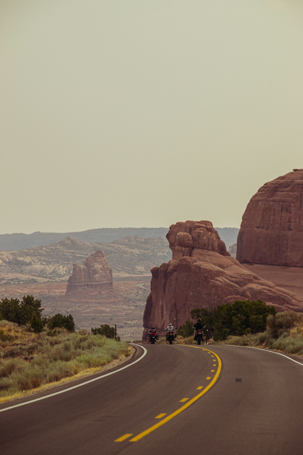 gray asphalt road between brown rock formation during daytime