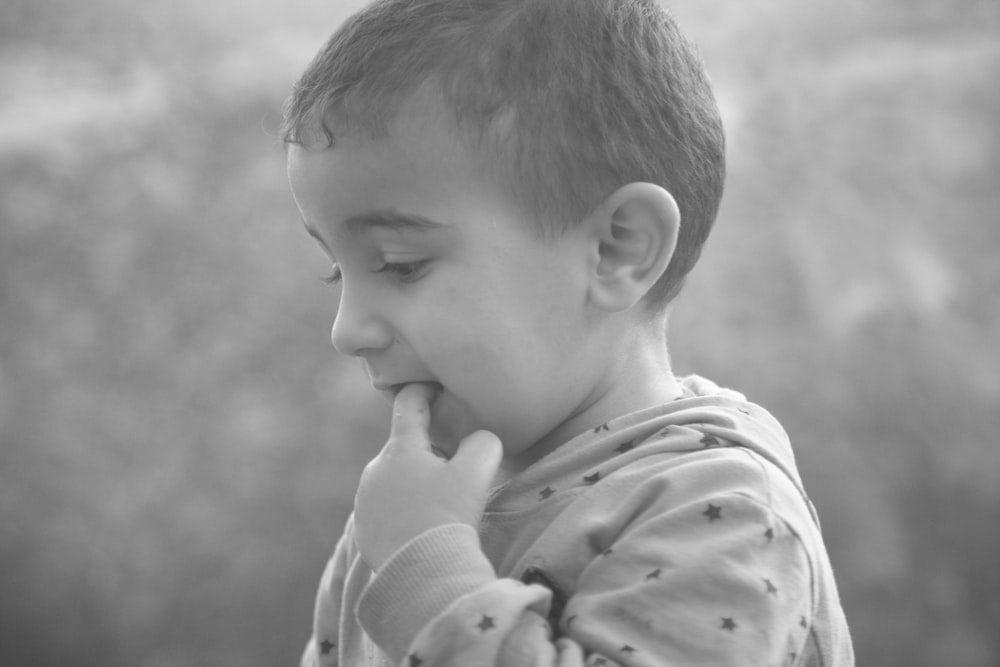 Graustufenfoto eines Jungen im weißen Langarmhemd