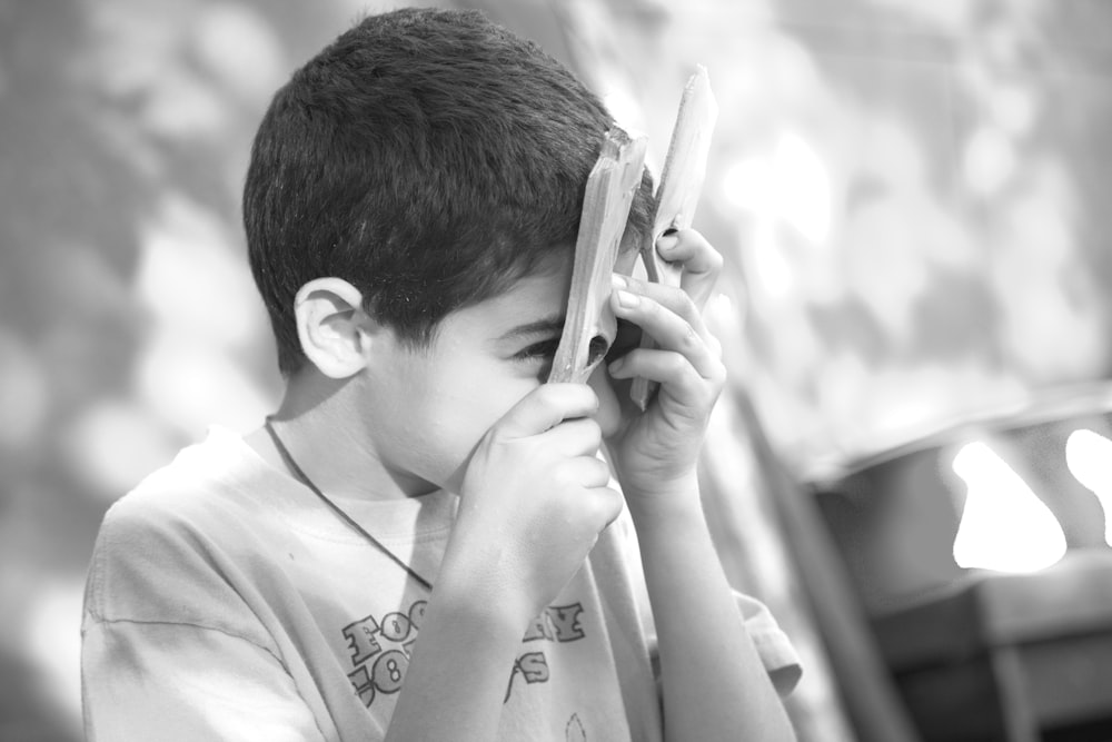 boy in white crew neck t-shirt using white smartphone