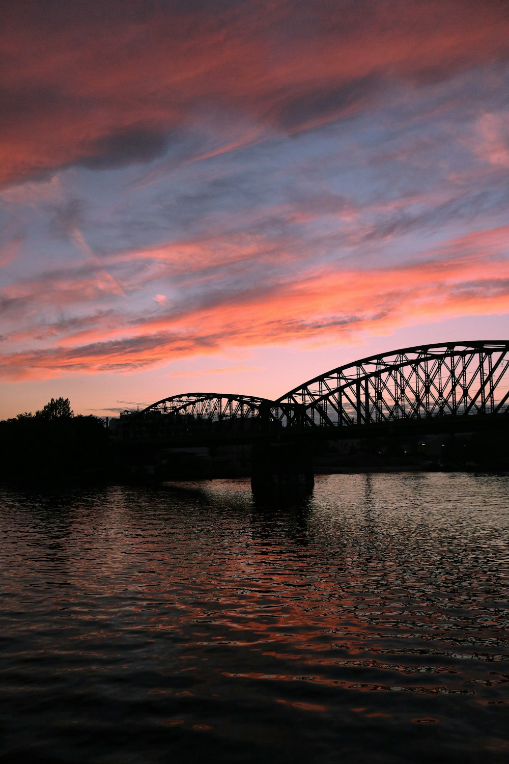 silhouette of bridge over river during sunset