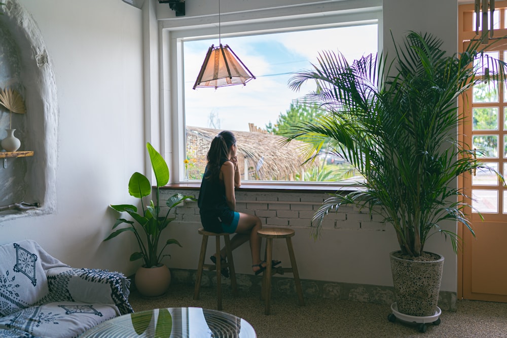 woman in black tank top and blue denim shorts sitting on brown wooden chair