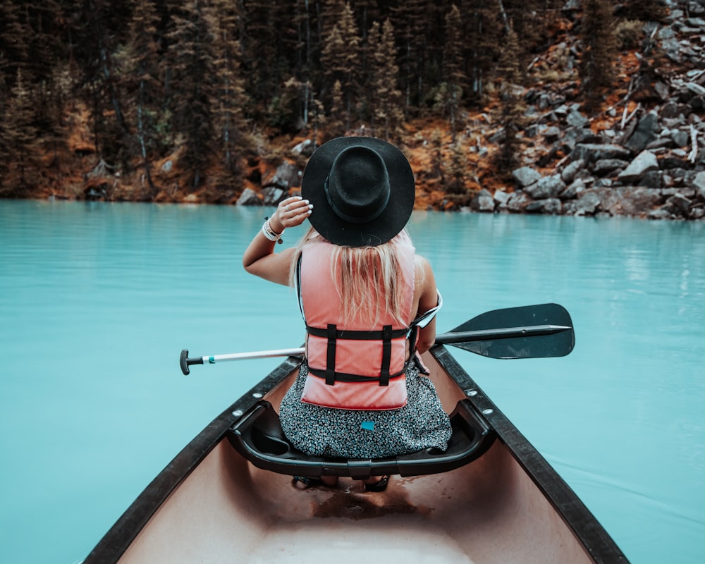 a woman in a hat is in a canoe