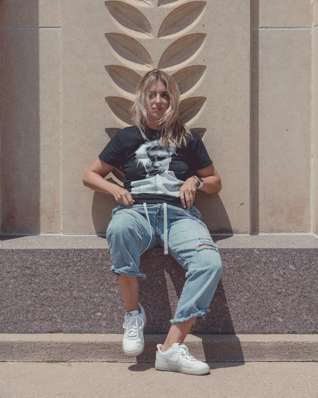 woman in black t-shirt and blue denim jeans sitting on concrete stairs