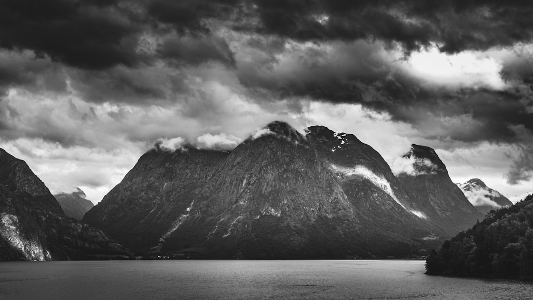 grayscale photo of mountain near body of water