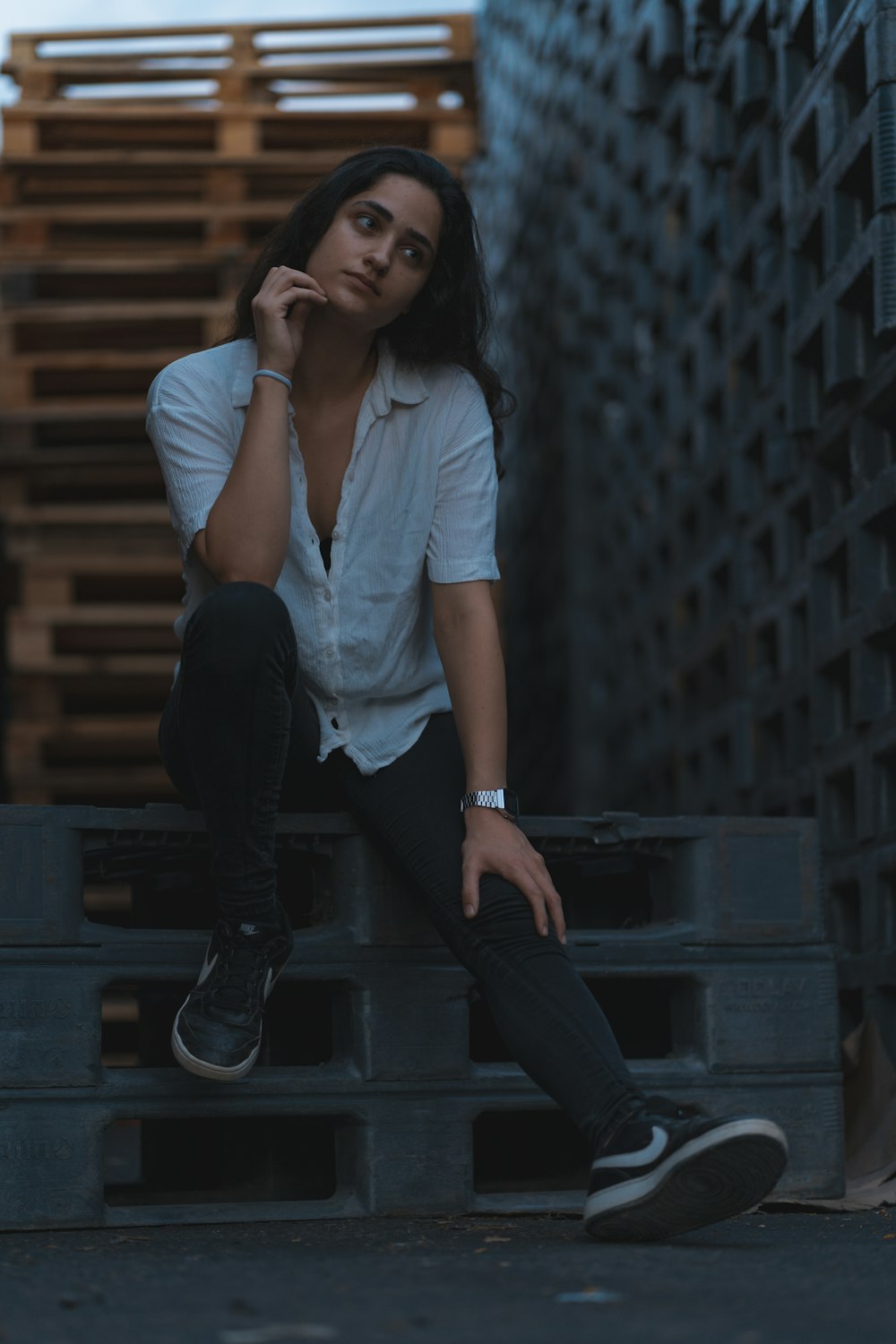 woman in white shirt and black pants sitting on black wooden stairs