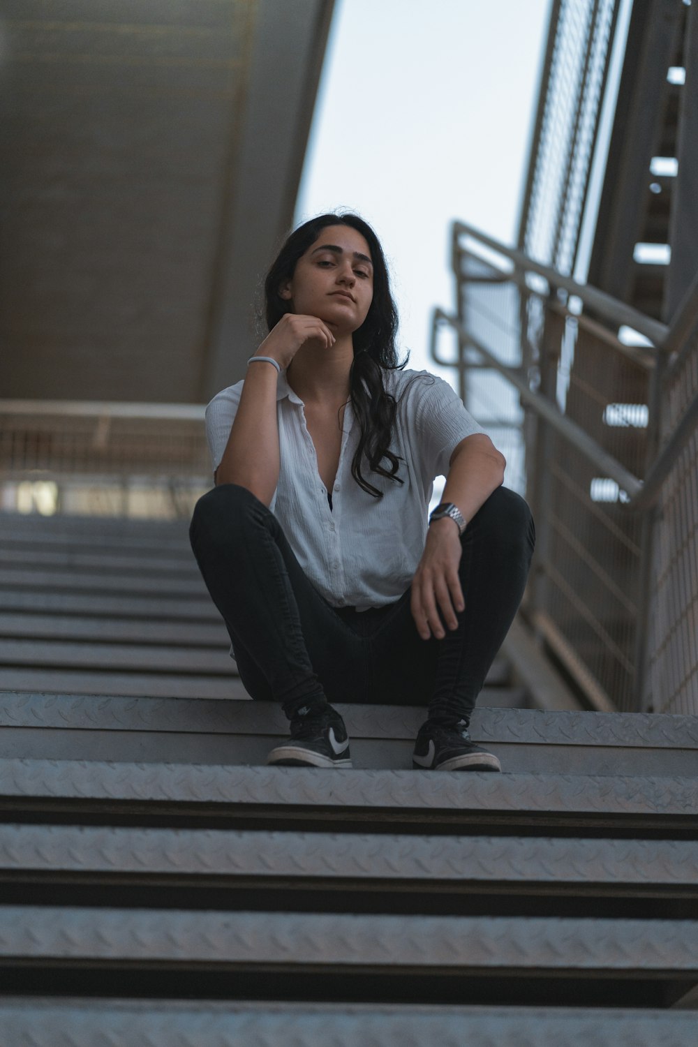 woman in white shirt and black pants sitting on stairs