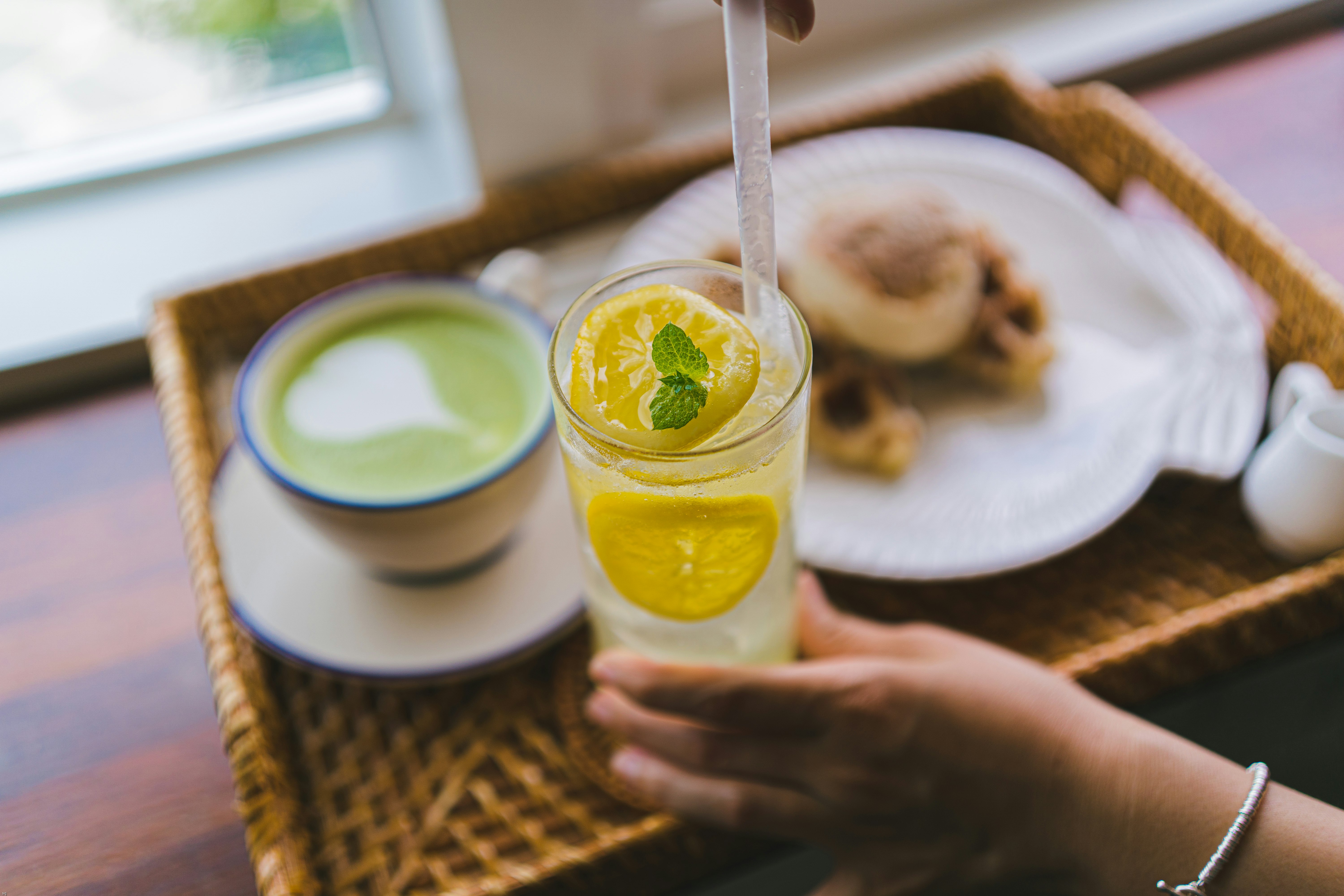 person holding clear drinking glass with yellow liquid