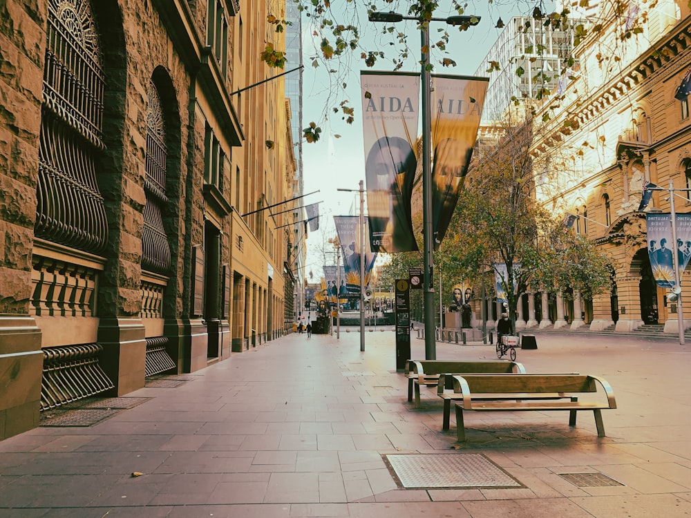 brown wooden bench on sidewalk during daytime