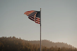 A rugged veteran proudly wearing a bold patriotic t-shirt standing in front of an American flag.