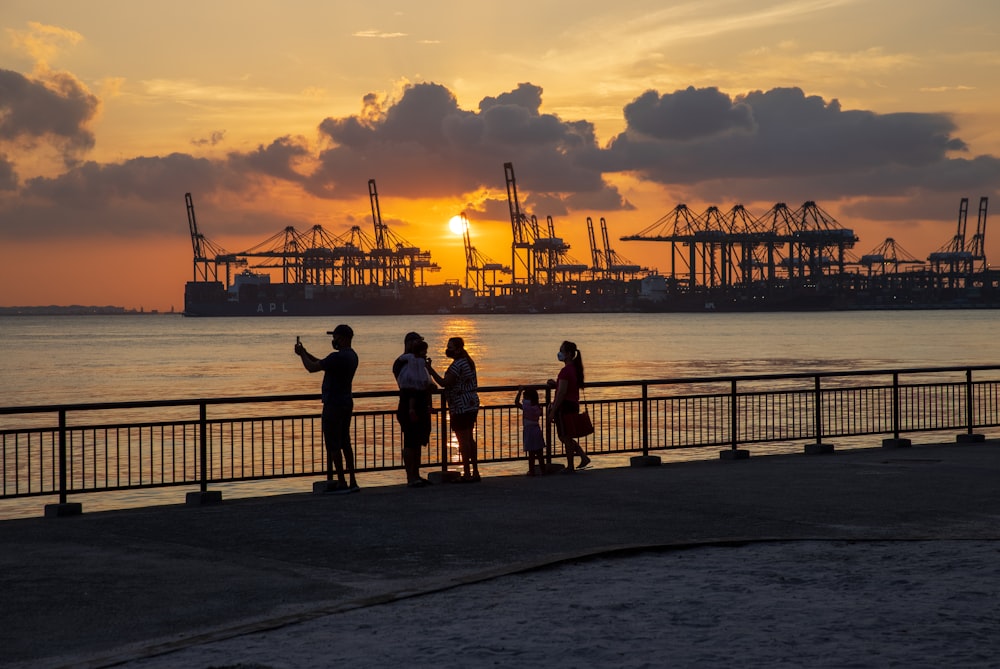 silhouette of people standing on beach during sunset