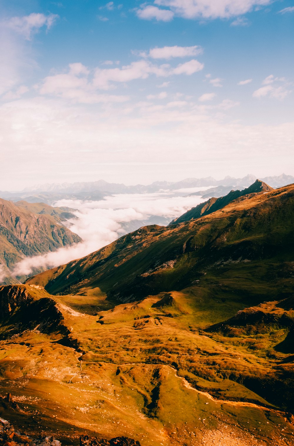 Braune und grüne Berge unter weißen Wolken tagsüber