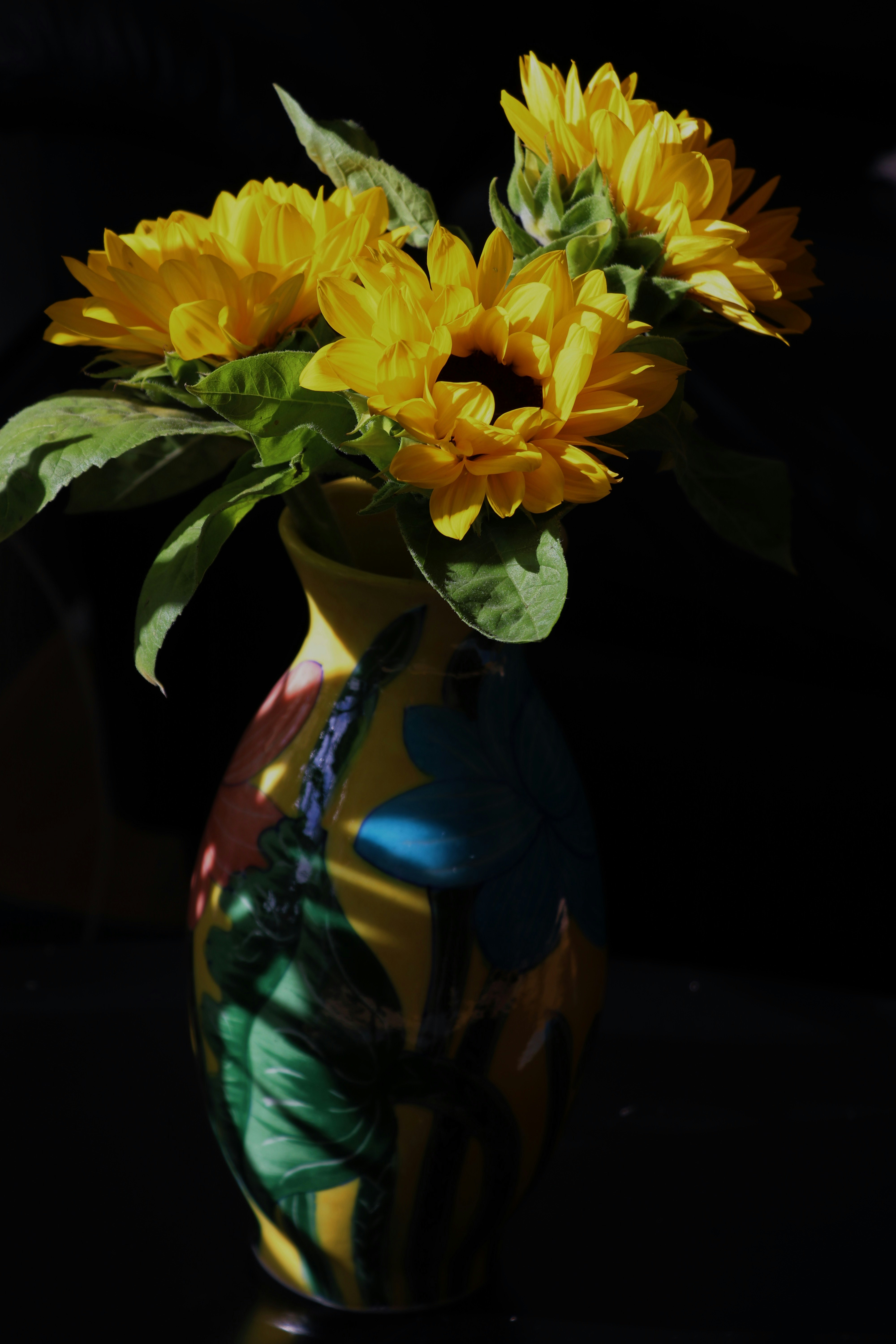 yellow flowers in blue and green ceramic vase