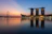 Photo of a smiling Singaporean businessman standing near Marina Bay Sands with the city skyline softly lit in the background.