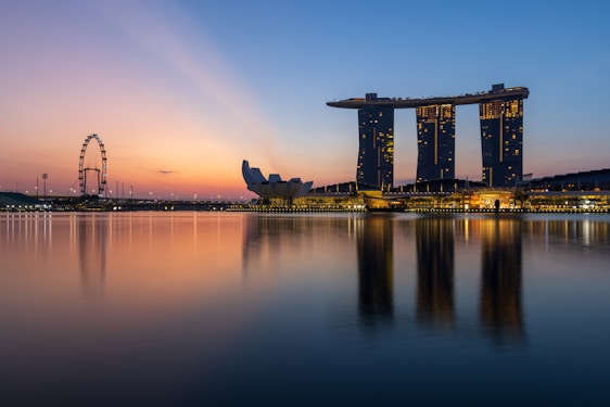 A panoramic view of Singapore’s Marina Bay skyline at dusk, with glowing skyscrapers and the iconic Gardens by the Bay lit up.