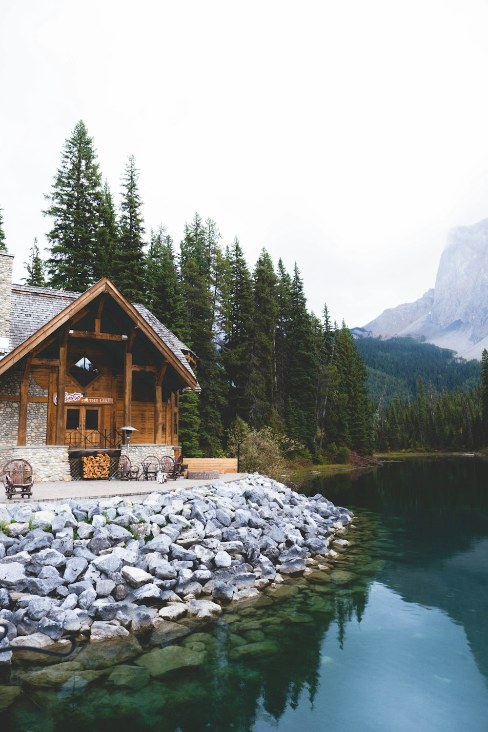 Maison en bois brun près du lac entourée d’arbres verts pendant la journée