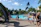 Family enjoying a sunny afternoon at a community park with a swimming pool and sports courts.
