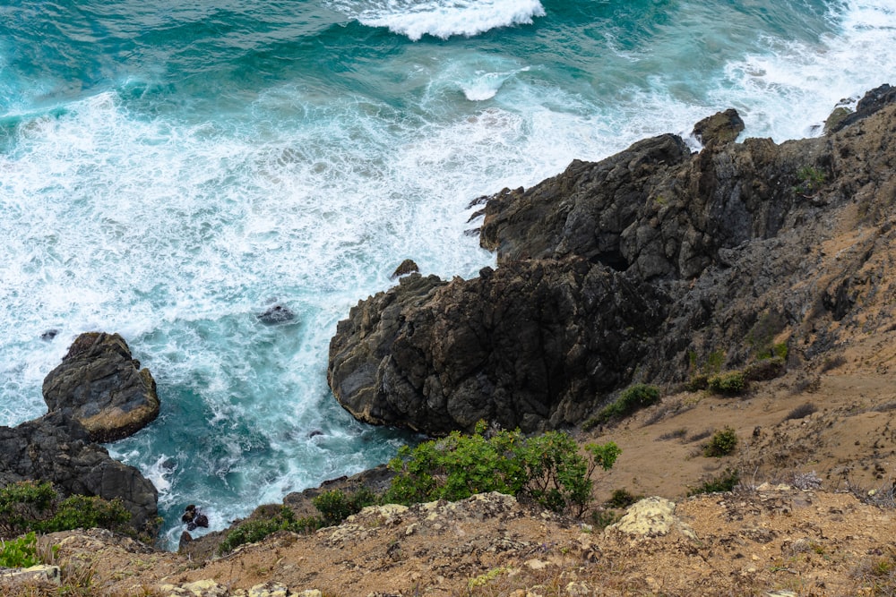 person standing on rock formation near sea during daytime