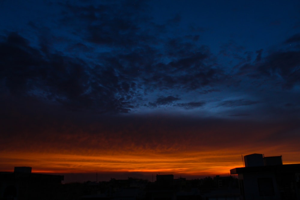 silhouette of buildings under cloudy sky during sunset