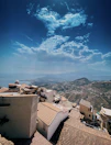 View from the window showing terracotta rooftops and olive trees under a clear sky.