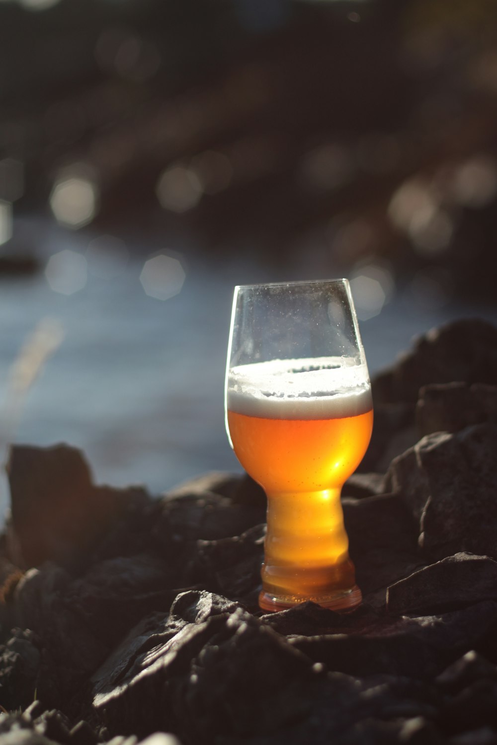 clear drinking glass with brown liquid on rock