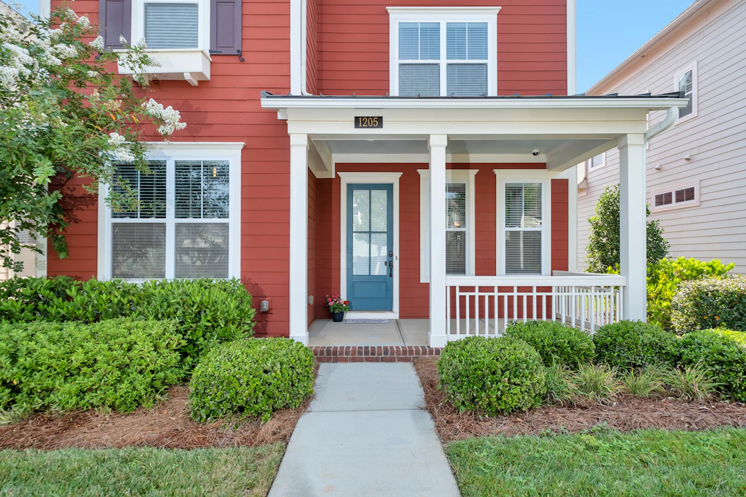 Two-storey house with red siding, white trim and porch, and a blue front door