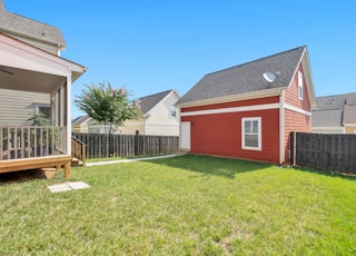 red and white wooden house on green grass field during daytime