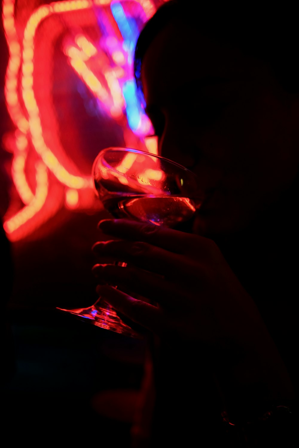 person holding clear wine glass with red light