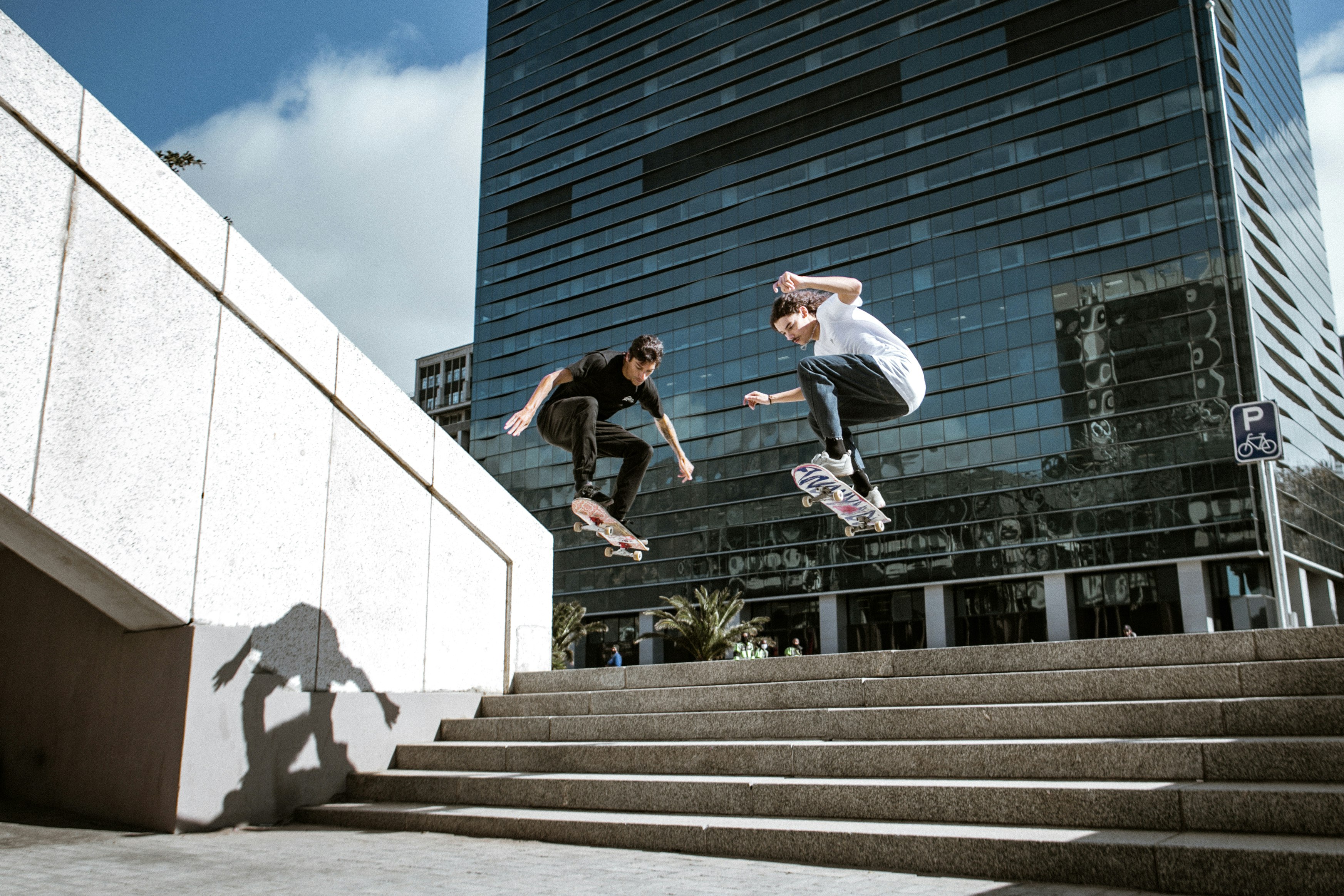 man in white shirt and black pants jumping on gray concrete stairs during daytime