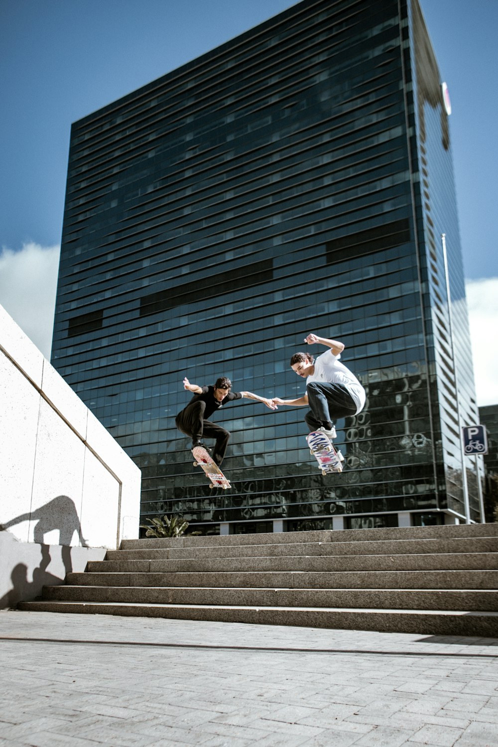 man in white shirt and black pants jumping on gray concrete stairs during daytime