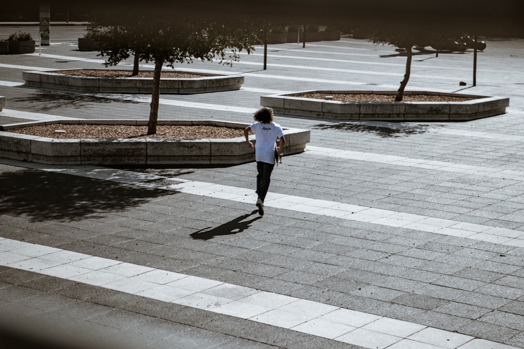 woman in white jacket walking on sidewalk during daytime