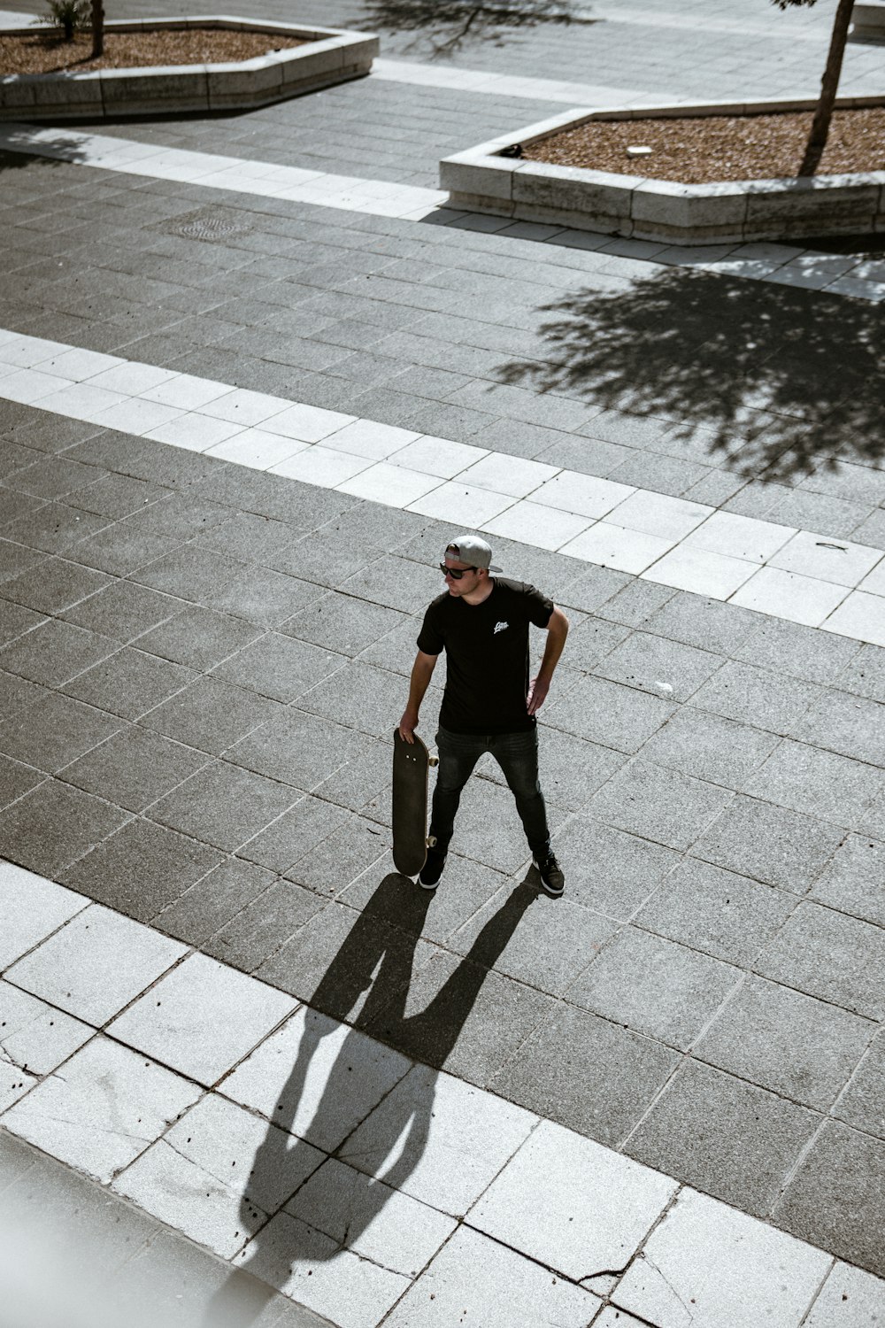 man in black t-shirt and black pants standing on gray concrete brick floor during daytime