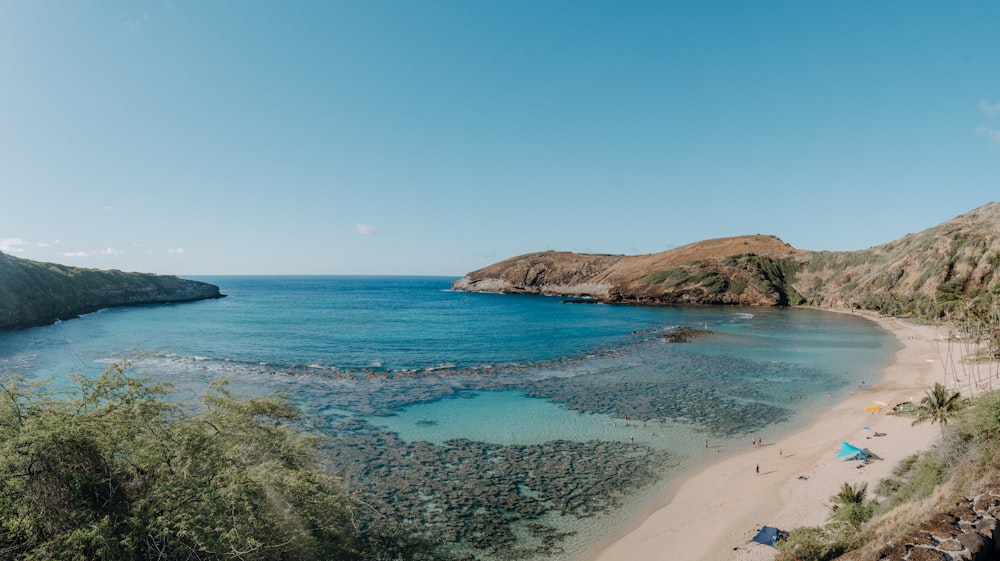 green and brown mountain beside blue sea under blue sky during daytime