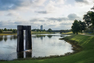 green grass field near lake under white clouds during daytime