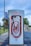 A series of Tesla electric vehicle superchargers are lined up in a visually appealing manner, creating a sense of depth and repetition. The background includes trees and a banner for the Arlington Expo Center.