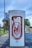 A series of Tesla electric vehicle superchargers are lined up in a visually appealing manner, creating a sense of depth and repetition. The background includes trees and a banner for the Arlington Expo Center.