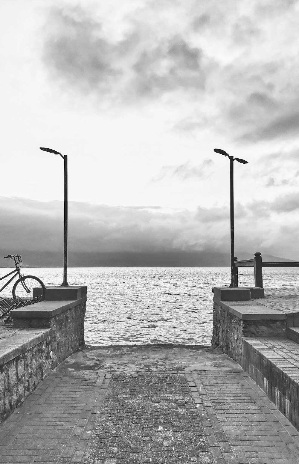 black bicycle on gray concrete dock near body of water