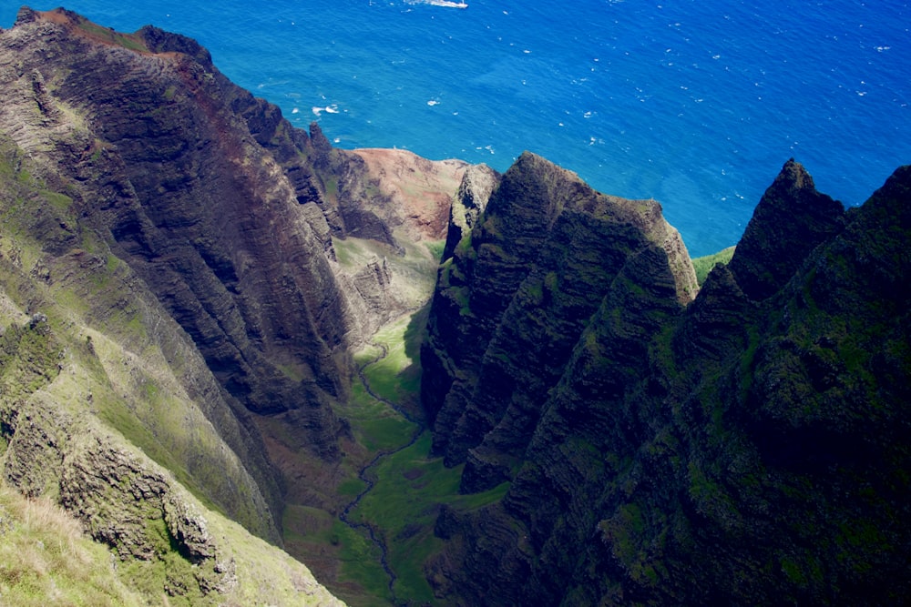 green and gray mountain beside blue sea during daytime