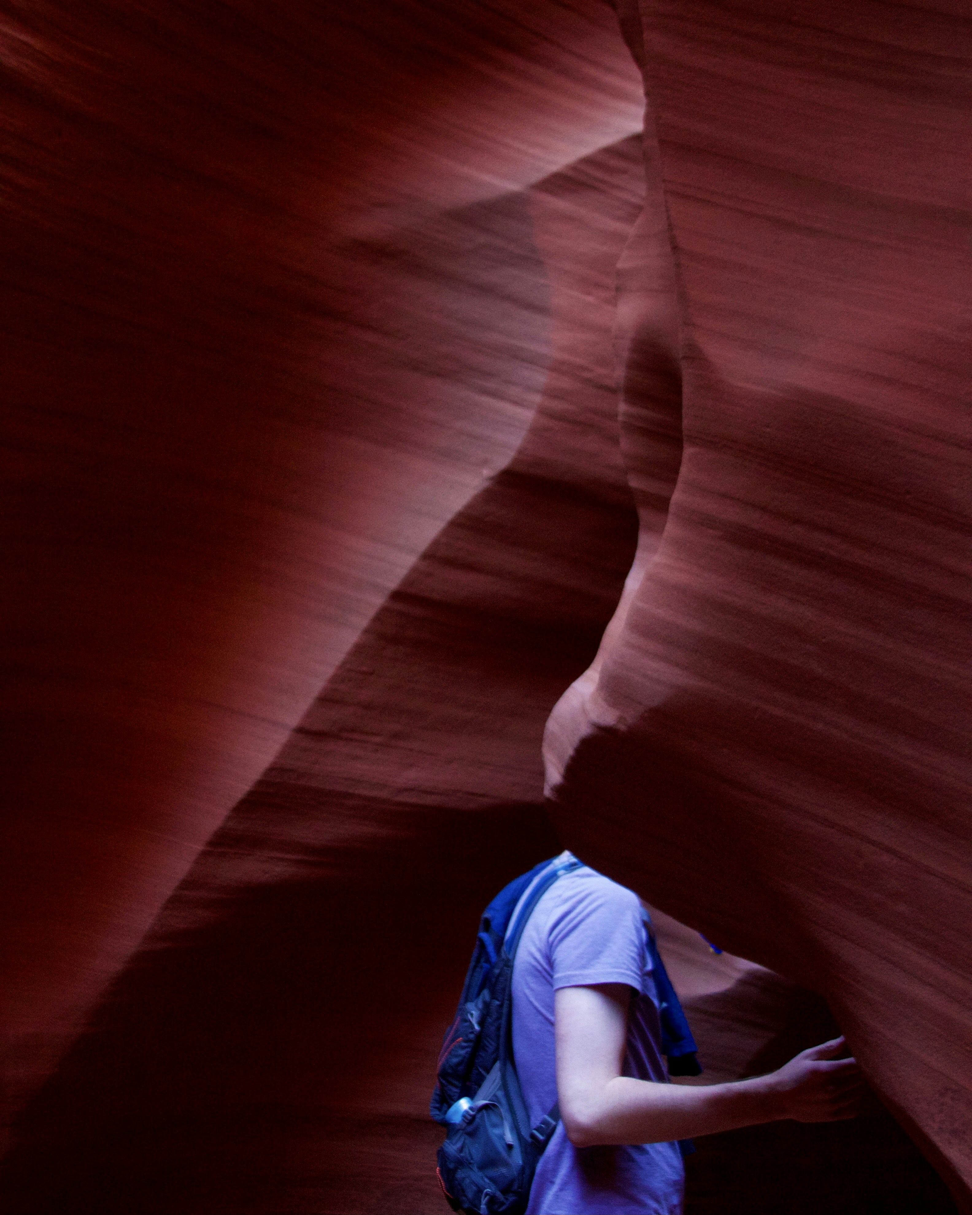 person in blue shirt and blue denim jeans sitting on brown rock formation