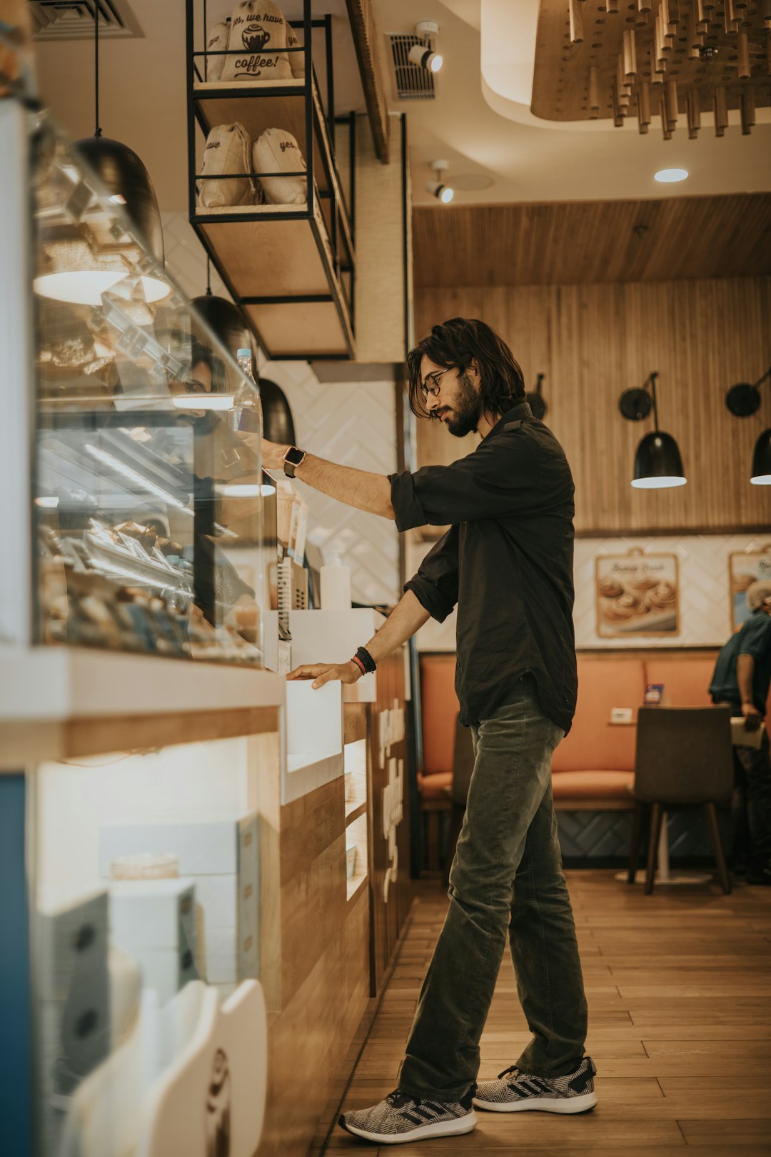 man in black long sleeve shirt and gray pants standing beside glass display counter