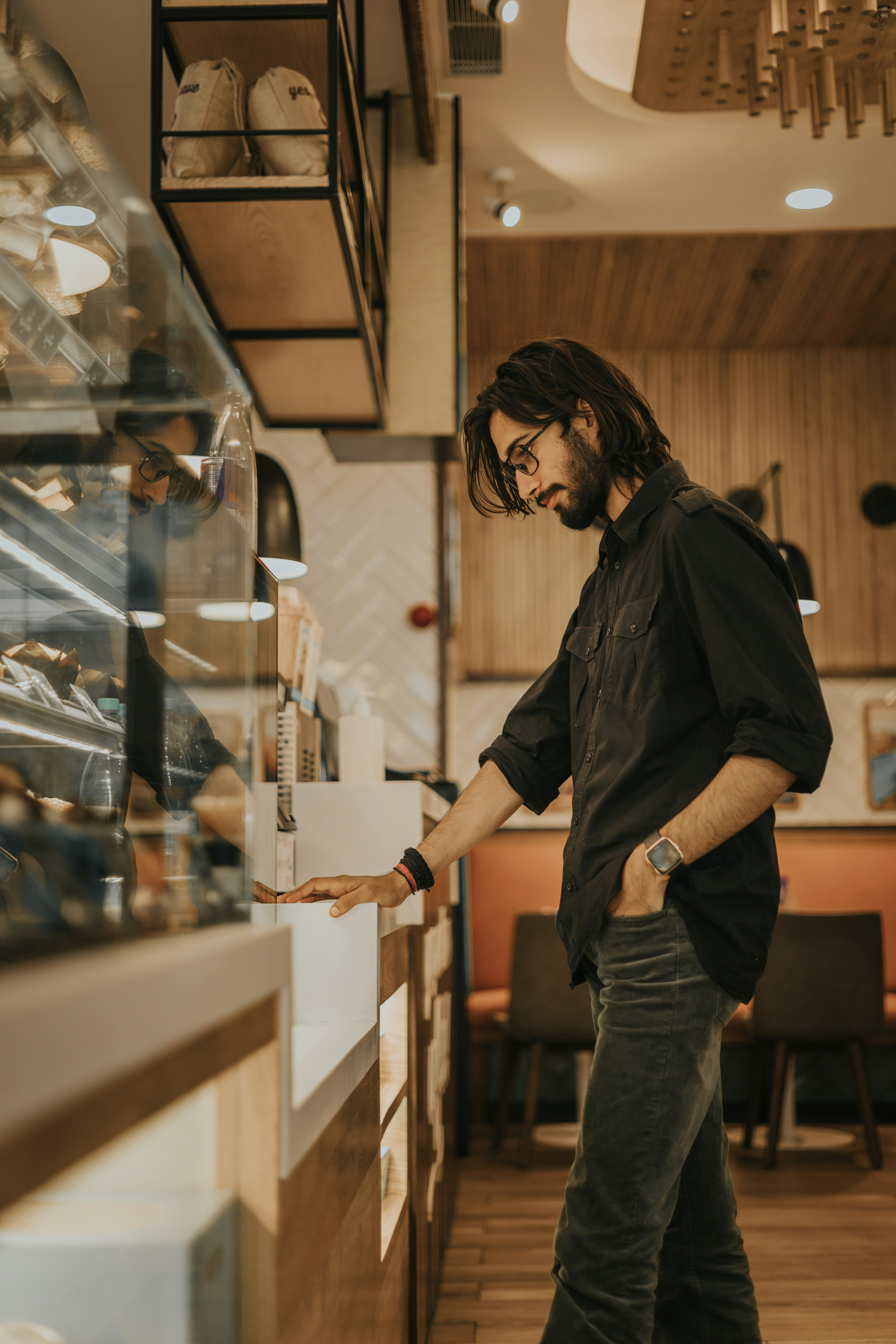 man in black button up shirt and gray denim jeans holding clear glass bottle